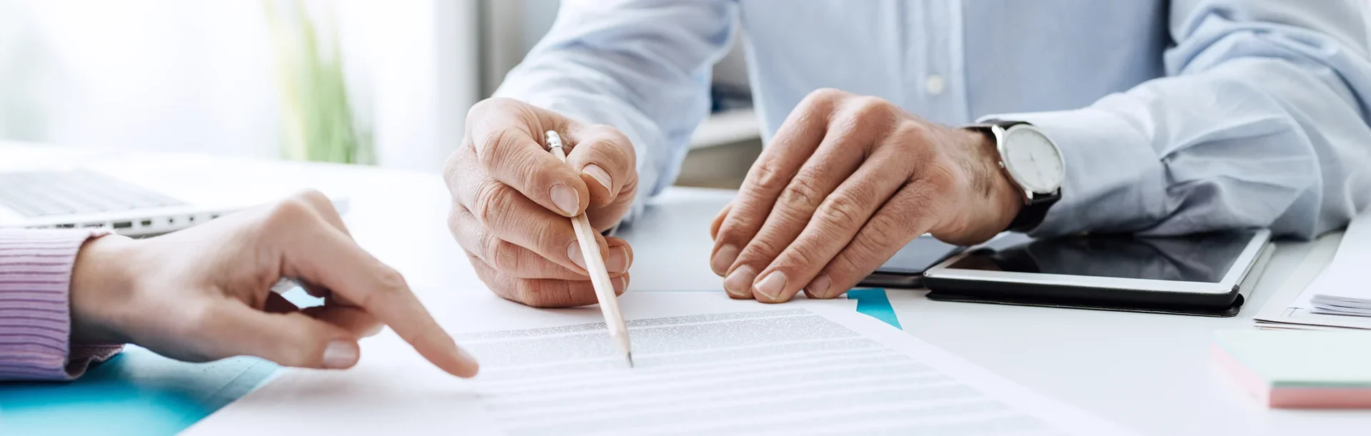 Two people reviewing and discussing a document, one pointing while the other holds a pencil over the paper.